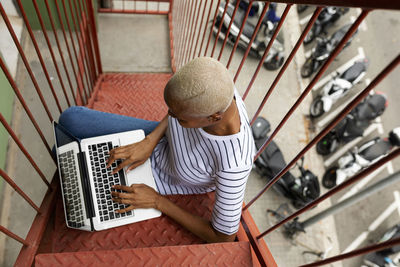 Woman sitting on outdoor stairs, using laptop