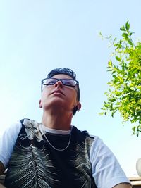 Low angle portrait of young man against sky