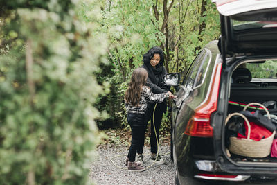 Full length of woman standing on car against trees