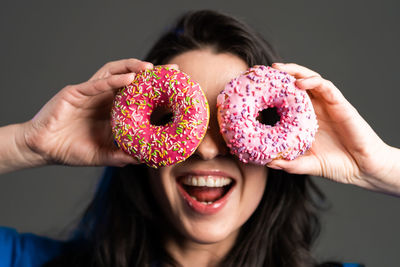 Woman holding donuts against gray background