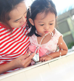 Low angle view of mother assisting daughter in drinking water through fountain