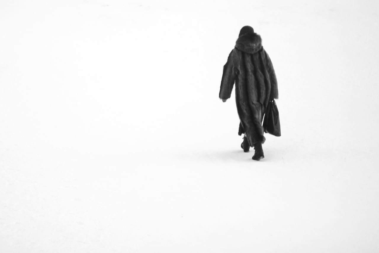 REAR VIEW OF A WOMAN WALKING ON SNOW COVERED LAND