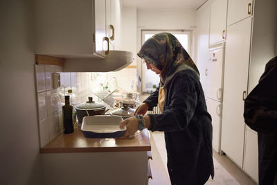 Woman in headscarf cooking dinner at home