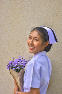 Portrait of a smiling young woman holding flower bouquet