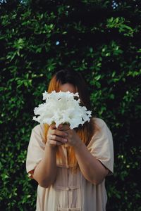 Midsection of woman holding umbrella while standing by plants