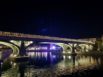 Arch bridge over river in city at night