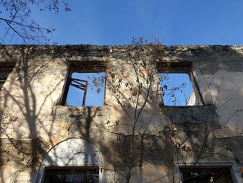 Low angle view of abandoned building against clear blue sky