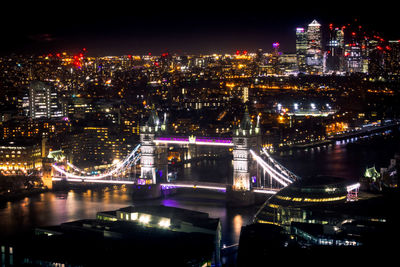 Illuminated bridge over river in city at night