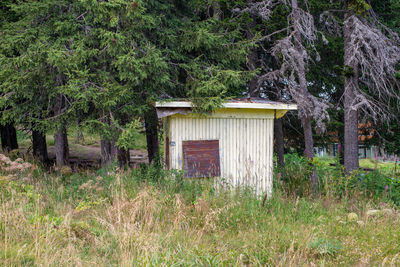 Wooden house on field by trees