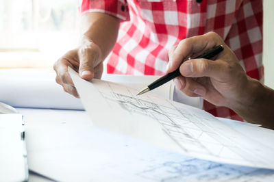 Midsection of man holding paper while sitting on table