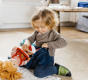 Cute girl wearing jeans to doll while playing at home