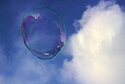 Low angle view of bubbles in mid-air against sky