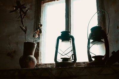 Close-up of electric lamp on table by window