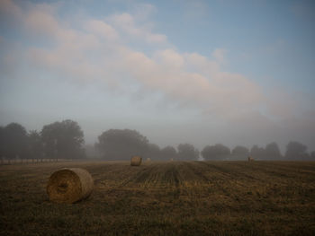 Hay bales on field against sky