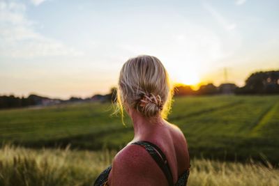 Rear view of woman on field against sky during sunset