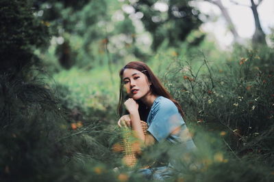 Portrait of young woman looking away on field