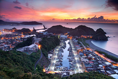 High angle view of cityscape by sea against sky during sunset