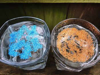 High angle view of glitters in glass on wooden table