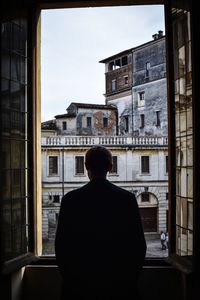 Rear view of man standing against buildings in city