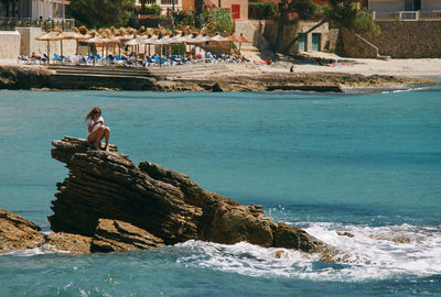 Tourists on rock by sea