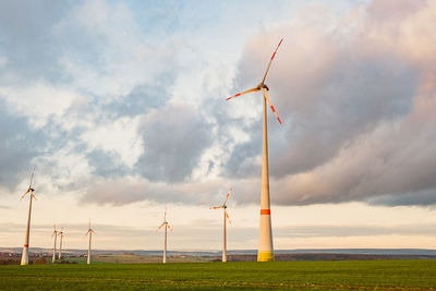 Wind turbines on field against sky