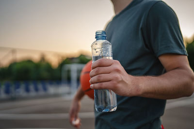 Midsection of man drinking water from bottle