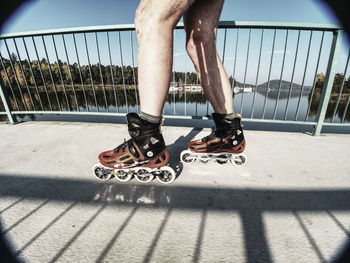 Man roller skater in speed hard shell skates. man try trick on the pathway against the sun