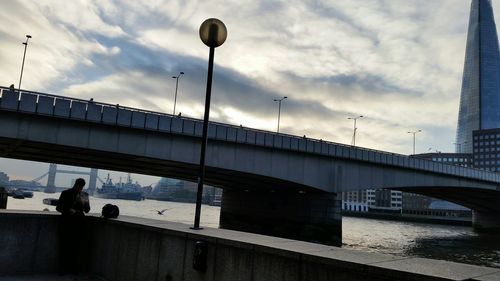 Low angle view of bridge over river in city against sky