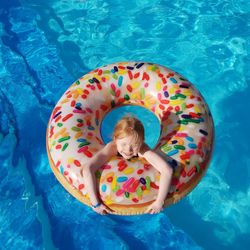 High angle view of smiling girl with inflatable ring in swimming pool