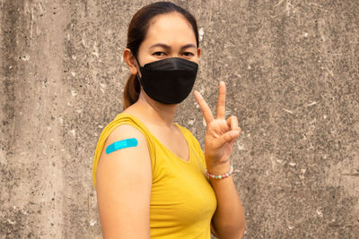 Portrait of woman standing against wall