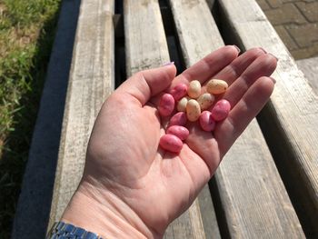 Cropped hand holding jelly beans on wooden bench