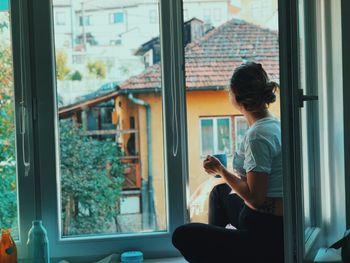 Woman with coffee mug sitting by window