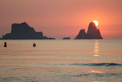 Scenic view of rocks in sea against sky during sunset