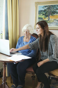 Grandmother and granddaughter using laptop together at home