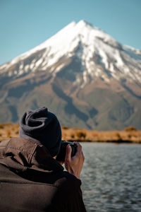 Rear view of man photographing on snowcapped mountain