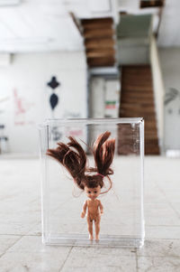 Close-up of doll in glass container on floor at home