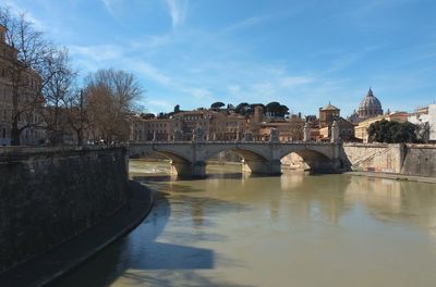 Arch bridge over river against sky in city