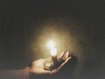 Close-up of hand holding illuminated candle