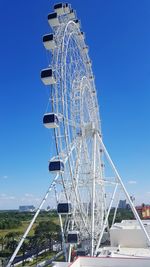 Low angle view of ferries wheel against blue sky