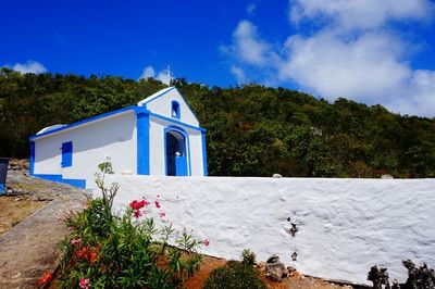 Built structure by trees against blue sky