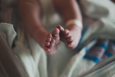 Low section of baby relaxing on bed