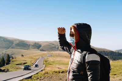 Side view of man with mask standing on mountain road