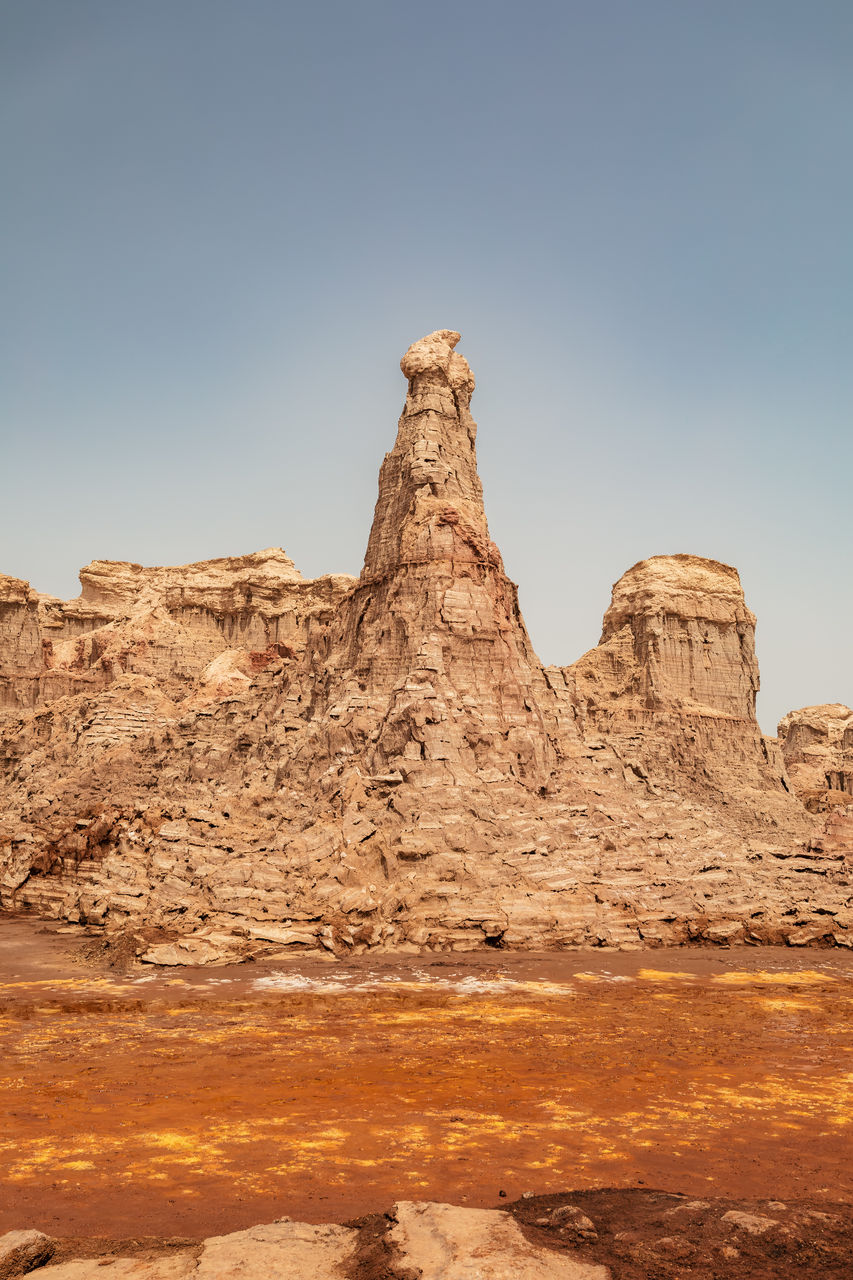 rock, landscape, natural environment, sky, scenics - nature, rock formation, environment, nature, desert, travel destinations, land, beauty in nature, travel, valley, wadi, no people, climate, geology, non-urban scene, clear sky, arch, plateau, arid climate, ancient history, tranquility, formation, outdoors, semi-arid, physical geography, day, tranquil scene, monument, remote, sunny, tourism, mountain, sunlight, extreme terrain, eroded, blue, sand, architecture