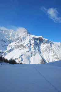 Scenic view of snowcapped mountains against blue sky