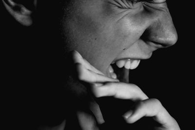 Close-up of man screaming by black background