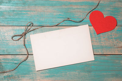 Close-up of heart shape on paper against blue wall