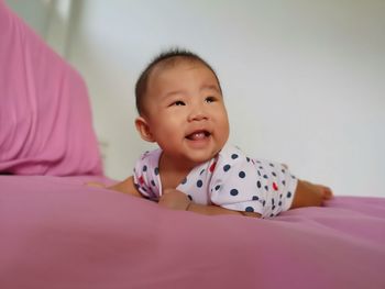 Portrait of cute baby lying on bed at home