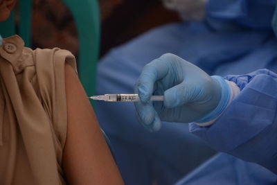 Midsection of doctor injecting vaccine to patient