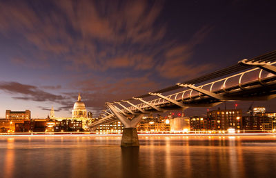 Illuminated city at waterfront during sunset