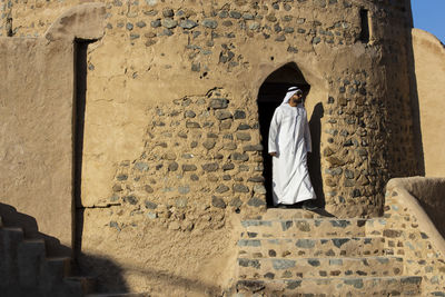 Rear view of woman standing against wall